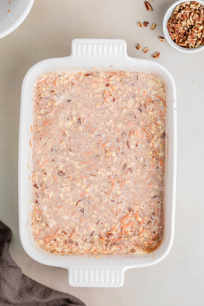 Carrot cake baked oatmeal mixture combined and spread evenly in a white baking dish.