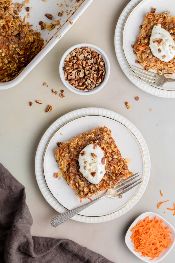 Plated carrot cake baked oatmeal topped with creamy frosting and chopped pecans.