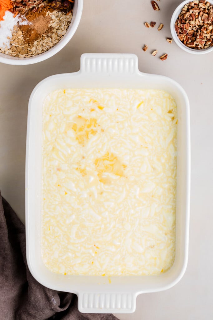 Wet carrot cake baked oatmeal mixture in a white baking dish.