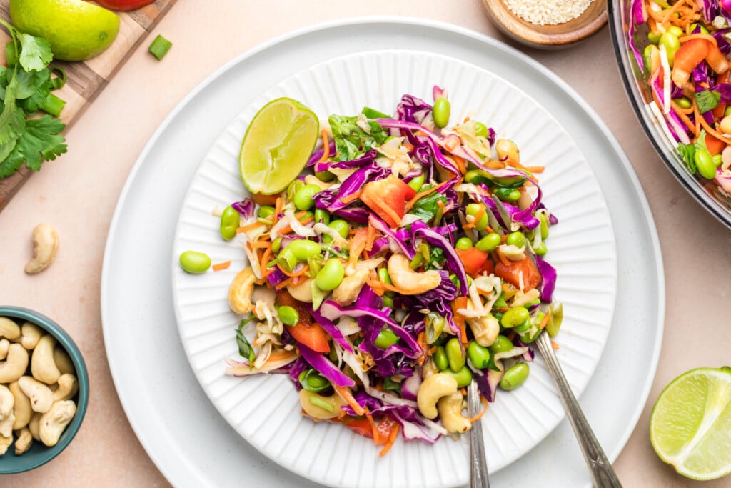 Plated edamame crunch salad served on a white plate with a lime wedge and fork.