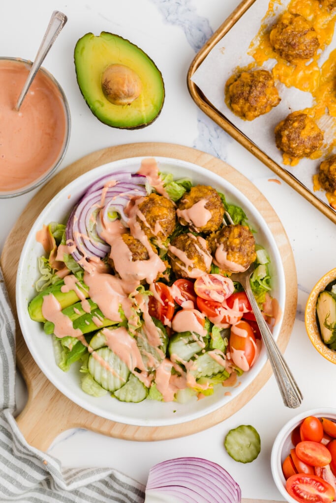 A bowl of salad with meatballs and vegetables.