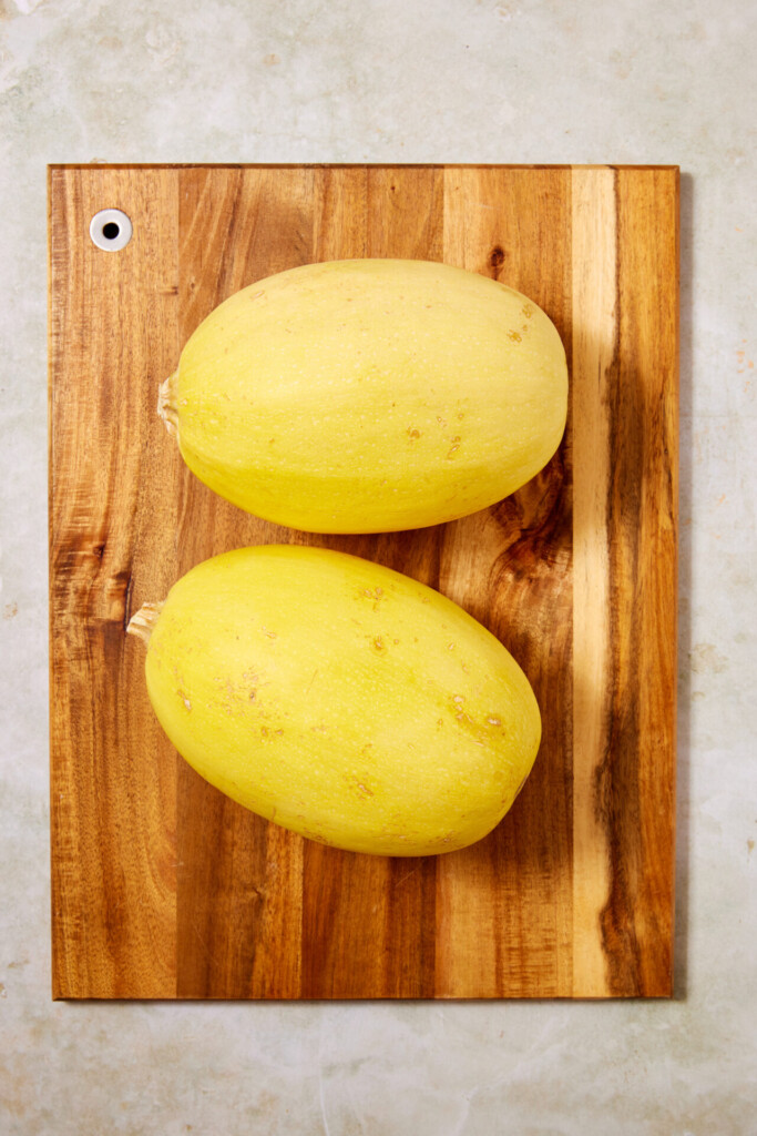 Two whole yellow spaghetti squashes are placed side by side on a wooden cutting board with a light background—perfect for preparing Turkey Meatballs with Spaghetti Squash.